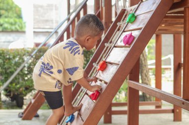 Küçük Asyalı çocuk dışarıda çocuk spor aletleri oynuyor.