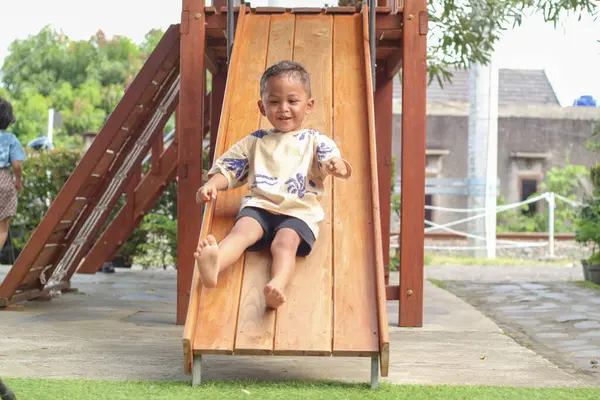 Okulda, anaokulunda ya da çocuk parkında sevimli Asyalı çocuk gülüşü oyunu. Çocuklar için sağlıklı bir yaz aktivitesi. Küçük Asyalı çocuk oyun alanında dışarı tırmanıyor. Çocuk dışarıda oyun oynuyor..
