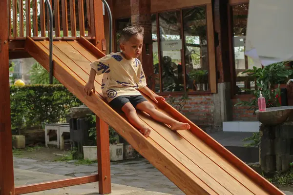 Asyalı çocuk kaygan bar oyuncağında oynarken gülümsüyor açık hava oyun parkında, mutlu anaokulu çocuğu yazın oyun parkında oynarken eğleniyor, küçük çocuk tırmanıyor.