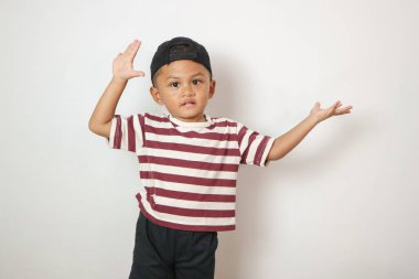 Sevimli çocuk gülümseyip el açıyordu. Açık beyaz renkli, izole edilmiş stüdyo fotoğrafıyla hoş geldin jesti yapıyordu.