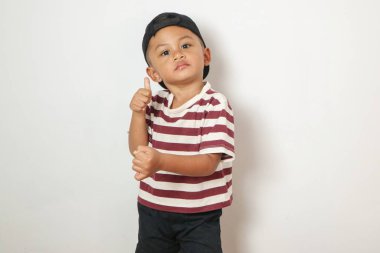 Asyalı sevimli çocuk mutlu bir şekilde gülümsüyor. Tayland üniforması giyiyor. Kırmızı pantolon, beyaz arka planda izole edilmiş parmak izini gösteriyor.