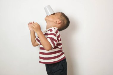 Beyaz arka planda süt içen Asyalı bir çocuk. Bir bardak sütle gülümseyen Asyalı çocuk..