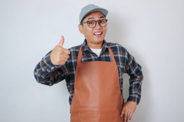 Kahverengi önlük giyen, kahve dükkanında çalışan gülümseyen Asyalı genç adam onaylanmış ve beyaz arka planda tavsiye edilen kameralara bakıyor. Küçük işletme başlangıç konsepti