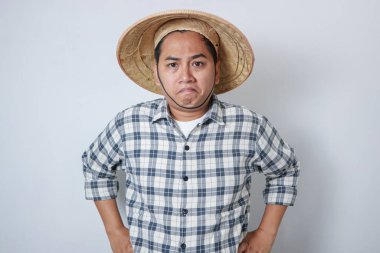 Kızgın Asyalı çiftçi bağırırken ayakta duruyor. Beyaz arkaplanda izole