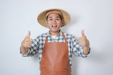 Konik şapka takan Endonezyalı çiftçi başparmağını uzatırken mutlu bir ifade sergiliyor..