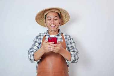 Endonezyalı genç çiftçi telefonuna bakarken heyecanla gülümsüyor.