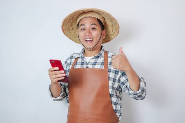Genç çiftçi gülümsüyor ve bir parmağını Whit akıllı telefonundan kaldırıyor.