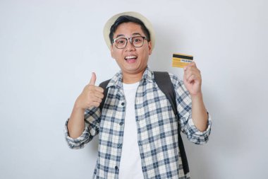 Altın bir kredi kartı tutarken parlak bir şekilde gülümseyen ve kendine güvenen Asyalı neşeli bir adam. Beyaz arkaplanlı stüdyoyu kapat.