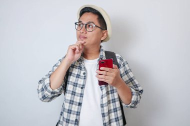 Genç Asyalı Yürüyüşçüler 'in telefonu kullandığından kuşkuluyum. Elleri çenesinde, beyaz arka planda.