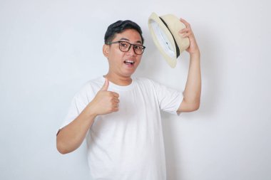 Beyaz arka planda beyaz gömlek giyen genç Asyalı adam elleriyle olumlu jest yapıyor, gülümsüyor ve başarı için seviniyor. Kazanan jest.