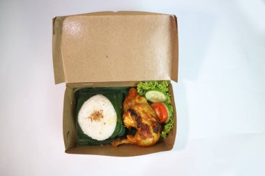 Ayam bakar (kızarmış tavuk) içeren Nasi Kotak, bir tepecik beyaz pirinç ve salatalık ve domates gibi taze sebzelerle servis edilir. düz konum fotoğraf konsepti
