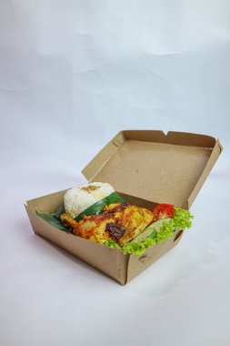 Lalapan Ayam: Pirinç kutusu, içinde ızgara tavuk pirinci, taze sebze ve biber sosu (sambal sosu) bulunan plastik bir tabakta servis ediliyor.).