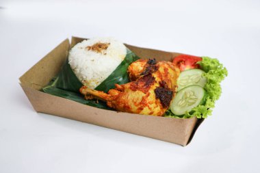 Izgara tavuk, pilav, biber ezmesi, bir dilim salatalık ve marul yaprağı ile servis edilir. Nasi ayam bakar lalapan, Endonezya ızgara tavuğunun otantik tarifi..