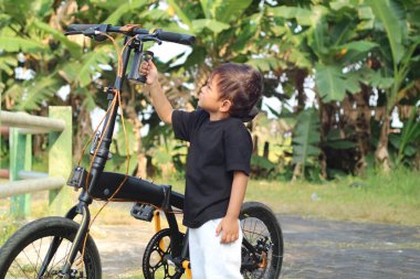 Mutlu Afrikalı Amerikalı çocuk yazın parkta bisiklet sürüyor.