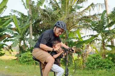 Mutlu Asya baba ve oğlu binicilik bisiklet bahar arka plan ile birlikte