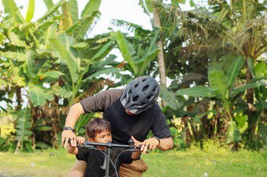 asya baba ve ilköğretim çağındaki oğlu bir parkta açık havada bisiklet sürme zevk.