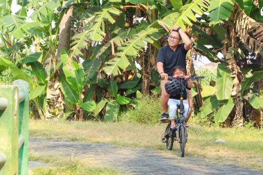 asya baba ve ilköğretim çağındaki oğlu bir parkta açık havada bisiklet sürme zevk.