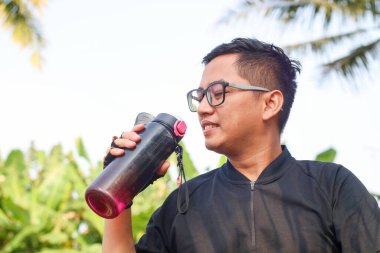 Şişeden su içen Asyalı bir sporcu. Spor ve Sağlıklı Yaşam Tarzı