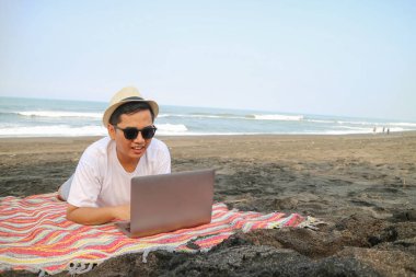 Serbest çalışan gezgin, dizüstü bilgisayar kullanan, internet kullanan. Plaj hamağında bilgisayarı olan bir adam. Yatta deniz yazı tatili. Doğa üzerine işyeri. İş gezisi, başarılı yaşam tarzı.