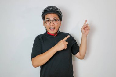 adult man looking excited and surprised pointing to the side. bike helmet and bicycle concept