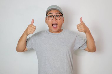 Heyecanlı Asyalı kurye ya da kurye beyaz bir arka planda izole edilmiş bir şekilde kameraya baş parmak hareketi yapıyor.