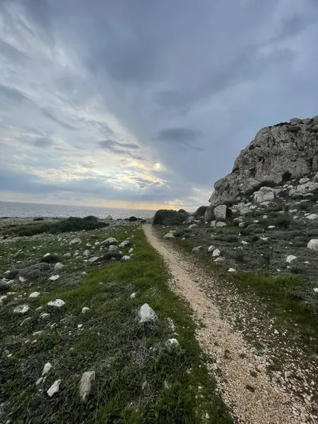 Serene Sahil Yolu Dramatik Rocky Cliff ve Huysuz Bulutlu Deniz Üzerinde Gün Batımı Ufkuna Giden Gökyüzü