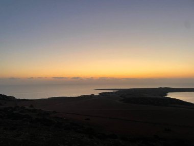 Kıbrıs Rum Kesimi 'nin Famagusta kentindeki Ayia Napa' da Cavo Greco üzerinde altın bir günbatımı. Huzurlu Akdeniz ve dramatik kıyı şeridi doğal güzelliğin huzurlu ve resimli bir sahnesine karışıyor..