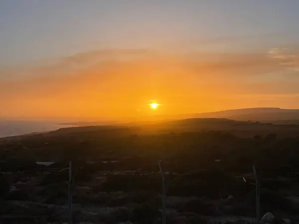 Bu nefes kesici fotoğraf Ayia Napa 'nın gün batımını canlı turuncu tonlarla banyo yaparken yakalıyor. Manzara yuvarlanan tepeleri, sakin bir güzellik atmosferi yaratıyor.