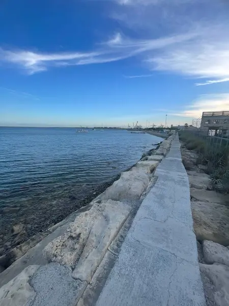 Kıbrıs 'ın Limasol kentindeki huzurlu kıyı yolunu keşfedin. Uçsuz bucaksız mavi sularda, engebeli kayaların üzerinde yürümek ufuk manzarası ve sakin bir gökyüzü, eğlence ve fotoğrafçılık için mükemmel..