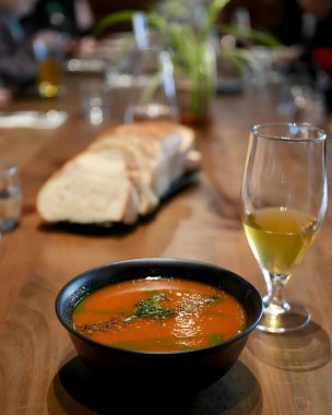 A bowl of rich tomato soup paired with fresh bread and a refreshing drink, set on a rustic table. A comforting culinary experience perfect for cozy gatherings and relaxation. clipart