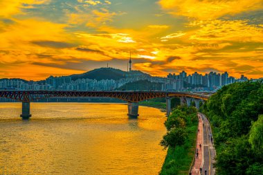 Namsan Kulesi 'nin arkasındaki günbatımında Seul, Güney Kore' de gökyüzünde altın bir parıltı yayılıyor.