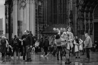 Köln, Almanya - 27 Ekim 2023: Köln Katedrali önündeki meydan bir kış günü ziyaretçilerle doludur. Gruplar fotoğraf, aile gezintisi için toplanır ve bireyler şehir sahnesine hakim olan görkemli Gotik mimariye hayran kalırlar.. 
