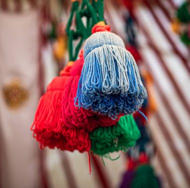 Fotoğrafta yeşil bir kabloda asılı duran parlak el yapımı yün ponpon kızlar görülüyor. Geleneksel yurtta dekoratif unsurlar olarak kullanılıyorlar..
