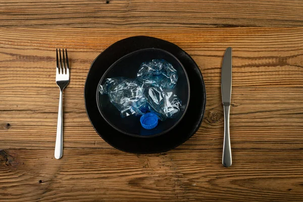 Eat Plastic, Blue Empty Plastic Bottle on Plate, Crumpled Plastic Bottle, Global Pollution Concept, Squashed Water Pet Bottles on Wood Background