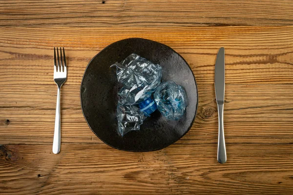 Eat Plastic, Blue Empty Plastic Bottle on Plate, Crumpled Plastic Bottle, Global Pollution Concept, Squashed Water Pet Bottles on Wood Background