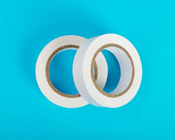 White Electrical Tape, Plastic Duct Tape Rolls, Colored Adhesive Tapes on Blue Background Top View