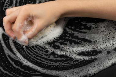 Natural Soapy Sponge with Foam, Eco Brown Sponges, Eco Friendly Hygiene Accessory, Scotch Brite Dishwasher in Hand on Black Background, Copy Space