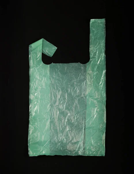 黒い背景の緑のプラスチック袋 買い物の後で粉砕されたプラスチック袋 セロファンの包装の廃棄物 使用された粉砕された使い捨て可能な袋 — ストック写真