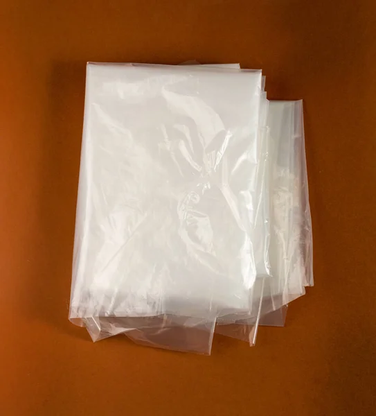 ブラウンの背景の折られた白いプラスチック袋 ショッピングの後で粉砕されたプラスチック袋 セロファンの包装の廃棄物 使用された粉砕された使い捨て可能な袋 — ストック写真