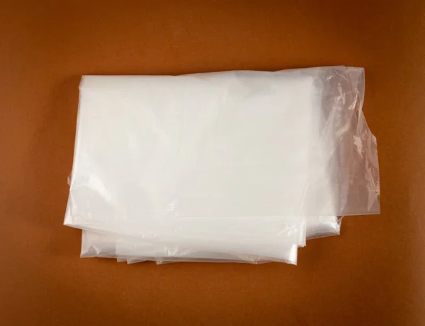 有褐色背景的折叠白色塑料袋 购物后的折叠塑料袋 雪洛芬尼包装废物 用过的折叠可处置邮袋 — 图库照片