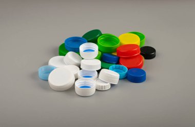 Plastik şişe kapağı yığını. HDPE Geri Dönüşüm Malzeme Grubu, Çember Polietilen Lid Seti, Gri Arkaplan Renkli Caps Grubu
