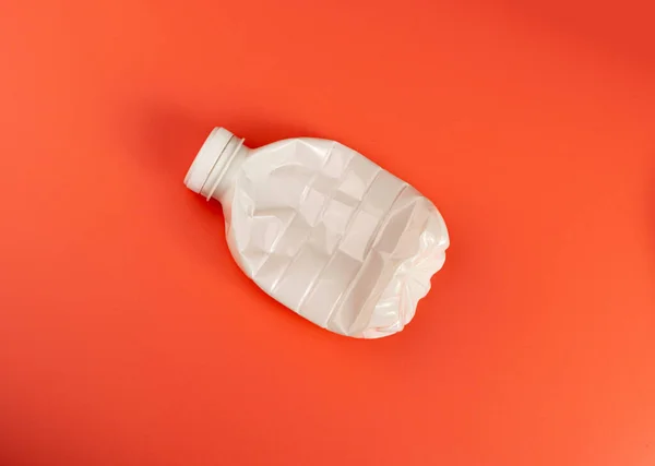空のプラスチック ミルク ボトル 粉砕された白いプラスチックびん 世界的な汚染の概念 赤い背景のスカッシュされたペットびん — ストック写真