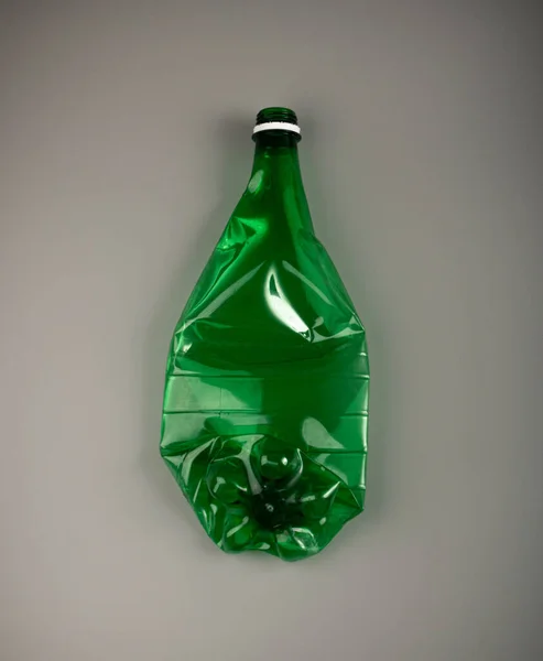 绿色空塑料瓶 皱折塑料瓶 全球污染概念 灰色背景下压扁水犬瓶 — 图库照片