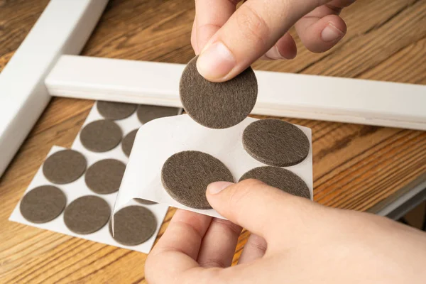 stock image Adhesive Felt Pads Floor Protectors, Anti-Skid Felt Stickers for Chair Legs, Hand Holds Anti-Noise Coating, Furniture Floor Care, Wooden Background