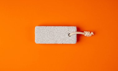 Orange Bacground 'daki sünger taşı, Grey Porous Lava Piece, Foot Care için Volkan Taşı, Basalt Extrusive Igneous Rock, Renk Arkaplanındaki Ayak Sağlığı Süngeri Taşı, Spa Konsepti