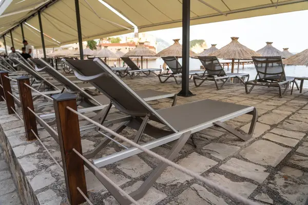 stock image Beach sunbeds, chairs on sandy beach on seaside resort, coastal town leisure area, relaxation, empty coastal chairs in morning light, oceanfront