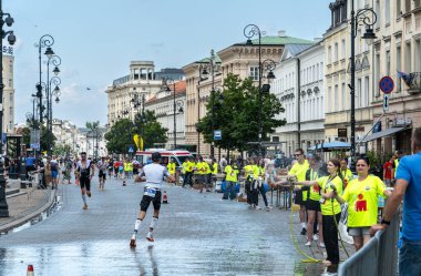 Varşova, Polonya, 9 Haziran 2024: Demir Adam triatlonu, demir adam uzun mesafe triatlon yarışları, genç Polonyalı gönüllüler eski Varşova şehir merkezinde koşuculara yardım ediyor, editoryal görüntü