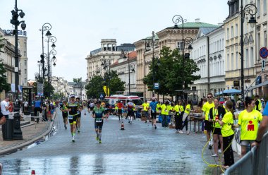 Varşova, Polonya, 9 Haziran 2024: Demir Adam triatlonu, demir adam uzun mesafe triatlon yarışları, genç Polonyalı gönüllüler eski Varşova şehir merkezinde koşuculara yardım ediyor, editoryal görüntü