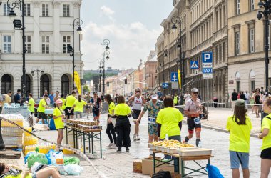 Varşova, Polonya, 9 Haziran 2024: Demir Adam triatlonu, demir adam uzun mesafe triatlon yarışları, genç Polonyalı gönüllüler eski Varşova şehir merkezinde koşuculara yardım ediyor, editoryal görüntü