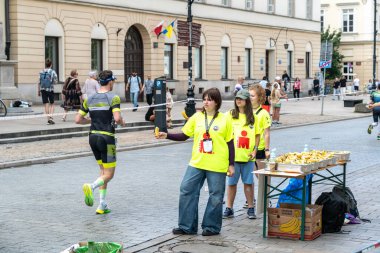 Varşova, Polonya, 9 Haziran 2024: Demir Adam triatlonu, demir adam uzun mesafe triatlon yarışları, genç Polonyalı gönüllüler eski Varşova şehir merkezinde koşuculara yardım ediyor, editoryal görüntü